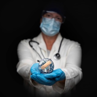 Nurse or doctor wearing face mask and surgical gloves holding bandaged planet earth