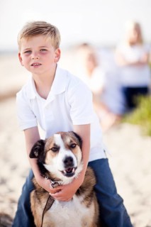 Handsome young boy playing with his dog at the beach