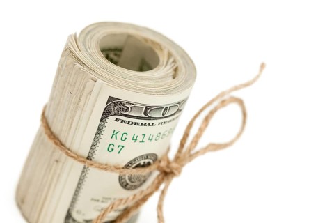 Roll of one hundred dollar bills tied in burlap string isolated on a white background