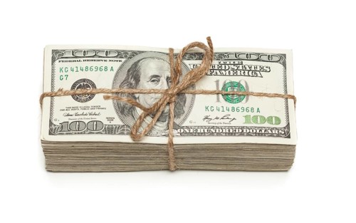 Stack of one hundred dollar bills tied in a burlap string isolated on a white background