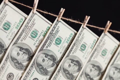 Hundred dollar bills hanging from a clothesline on a dark background