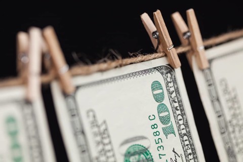 Hundred dollar bills hanging from a clothesline on a dark background