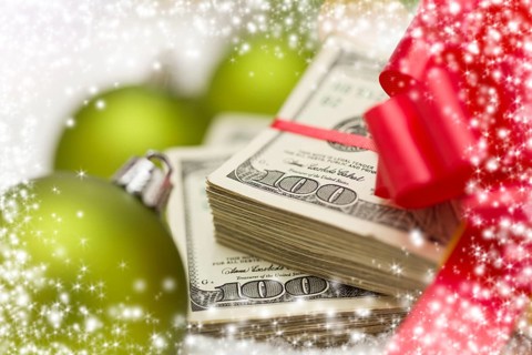 Stack of one hundred dollar bills with red bow near green christmas ornaments on snow flakes with snow flake border