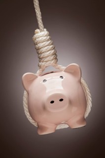 Piggy bank hanging in hangman's noose on spot lit background