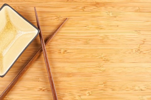 Bamboo textured surface background with chop sticks and bowl and plenty of room for text