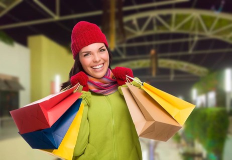 Pretty warmly dressed mixed-race woman in outdoor mall with shopping bags