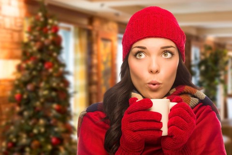 Warm mixed race woman wearing winter hat and gloves in christmas setting