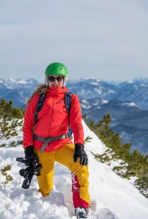 Young woman with camera at the summit of Simetsberg in winter
