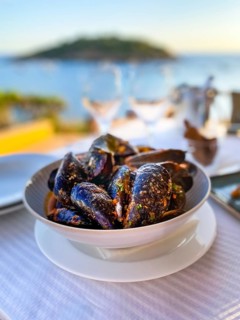 Mytilus (Mytilus) with tomato sauce and garlic in the evening sun by the sea