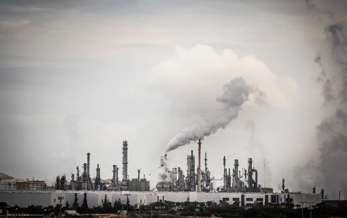 Working industrial plant with smoke stacks billowing smoke into the air