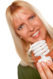 Attractive blonde woman holds energy saving light bulb isolated on a white background with narrow depth of field