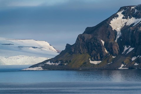 Green cliff in the glacier covered moutains of Franz Josef Land archipelago