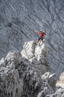 Young man sitting on rocks and waving