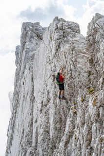 Young man climbing a vertical rock face without a rope