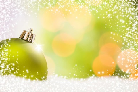 Beautiful matt green christmas ornament on snow flakes over an abstract snow and light background with room for your own text