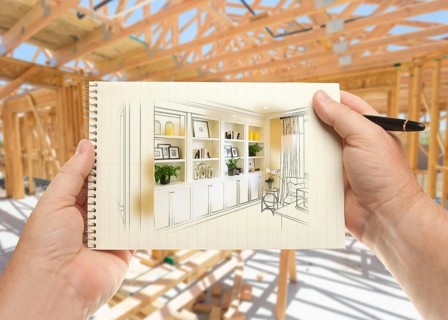 Hands holding pen and pad of paper with built-in shelves and cabinets inside house construction framing