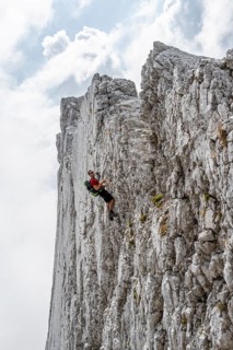 Young man climbing a vertical rock face without a rope