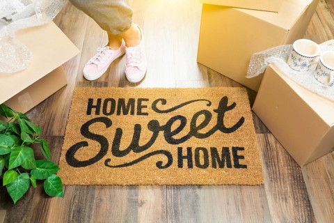 Woman in pink shoes and sweats standing near home sweet home welcome mat