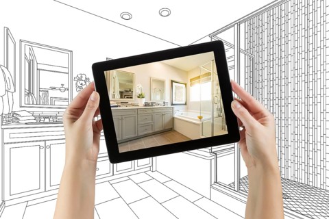 Hands holding computer tablet with master bathroom photo on screen and drawing behind