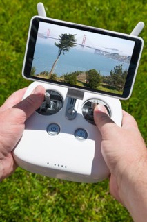 Hands holding drone quadcopter controller with golden gate bridge view on screen