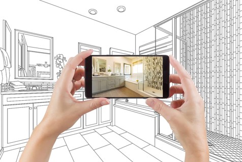 Hands holding smart phone with master bathroom photo on screen and drawing behind
