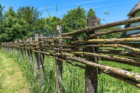 Wooden fence connected with thin branches in wickerwork