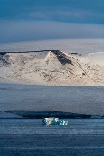 Iceberg floating before the flat table mountains covered with ice