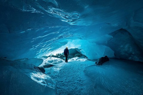 Man with headlamp in glacier cave
