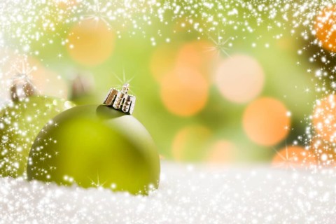 Beautiful matt green christmas ornaments on snow flakes over an abstract snow and light background with room for your own text