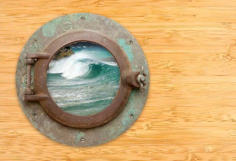Antique porthole with view of crashing waves on a bamboo wall background