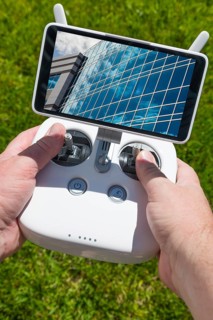 Hands holding drone quadcopter controller with corporate building on screen