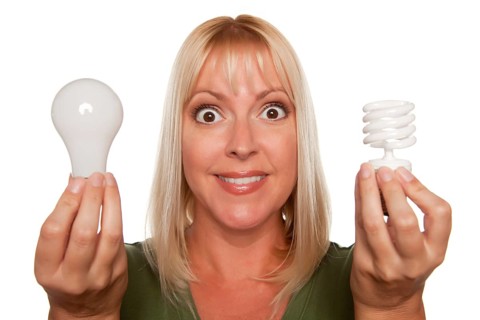 Woman holds energy saving and regular light bulbs isolated on a white background