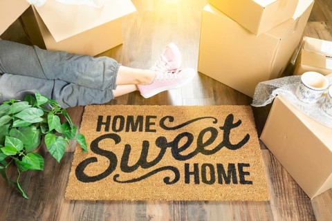 Woman wearing sweats relaxing near home sweet home welcome mat