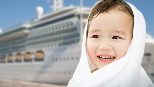 Happy mixed-race chinese and caucasian boy near cruise ship wrapped in A towel