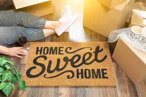 Woman wearing sweats relaxing near home sweet home welcome mat