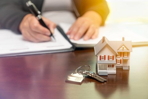 Woman signing real estate contract papers with house keys
