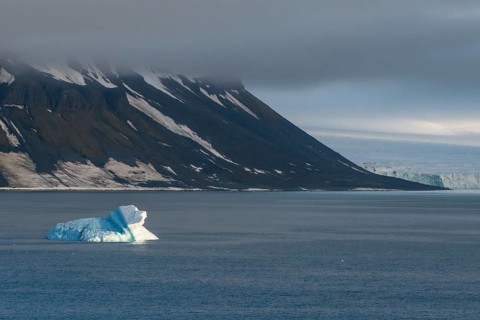 Iceberg floating before the flat table mountains covered with ice