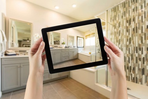 Master bathroom interior and hands holding computer tablet with photo on screen