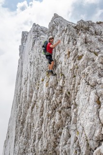 Young man climbing a vertical rock face without a rope