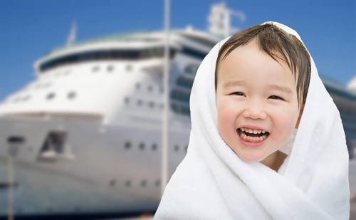 Happy mixed-race chinese and caucasian boy near cruise ship wrapped in A towel