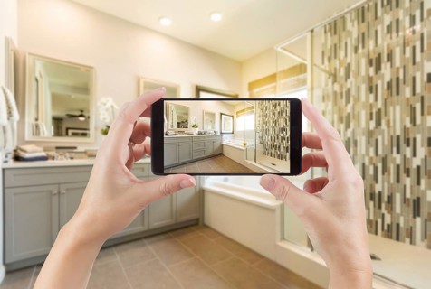 Master bathroom interior and hands holding smart phone with photo on screen