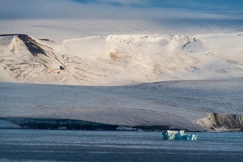 Iceberg floating before the flat table mountains covered with ice