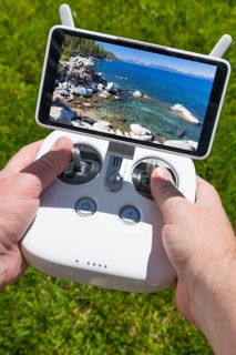 Hands holding drone quadcopter controller with beautiful lake view on screen