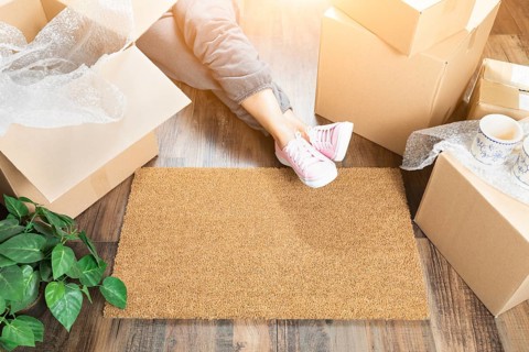 Woman wearing sweats relaxing near home sweet home welcome mat