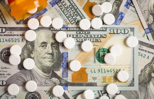 Medicine pills scattered on newly designed U.S. one hundred dollar bills