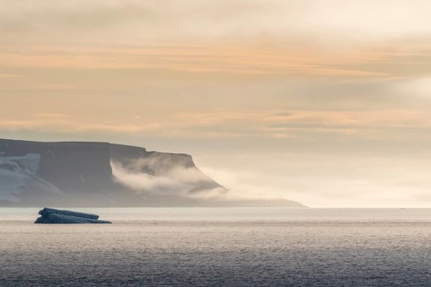 Iceberg floating before the flat table mountains covered with ice