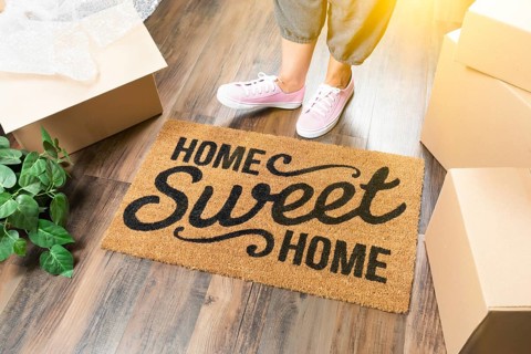 Woman in pink shoes and sweats standing near home sweet home welcome mat