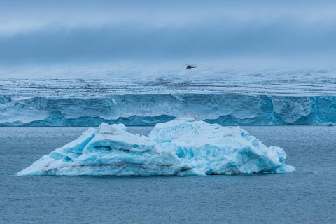 Helicopter flying over a very huge glacier on Mc Clintok or Klintok Island