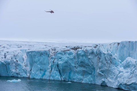 Helicopter flying over a very huge glacier on Mc Clintok or Klintok Island
