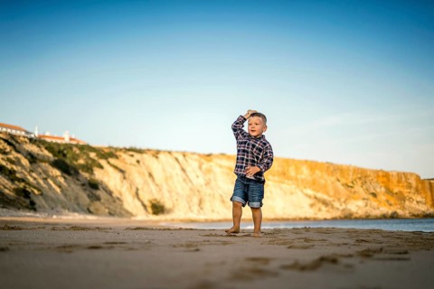 Small boy throwing stones on the beach by the sunset